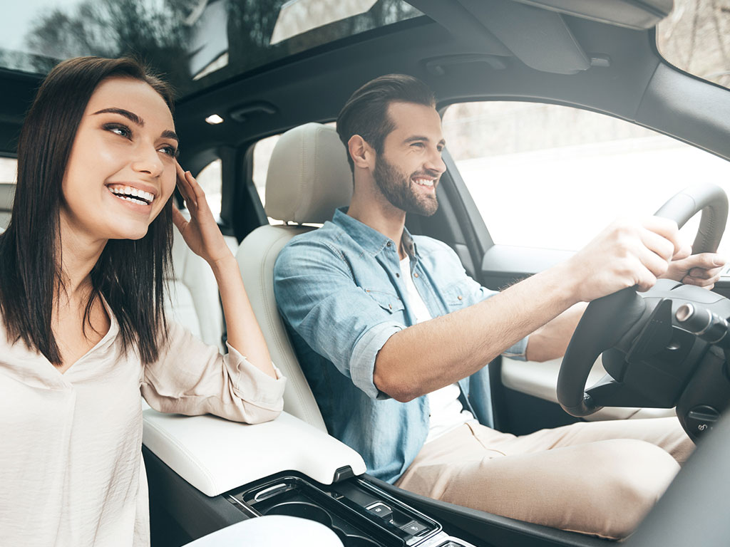 Happy couple driving after completing driving lessons at Success Driving School